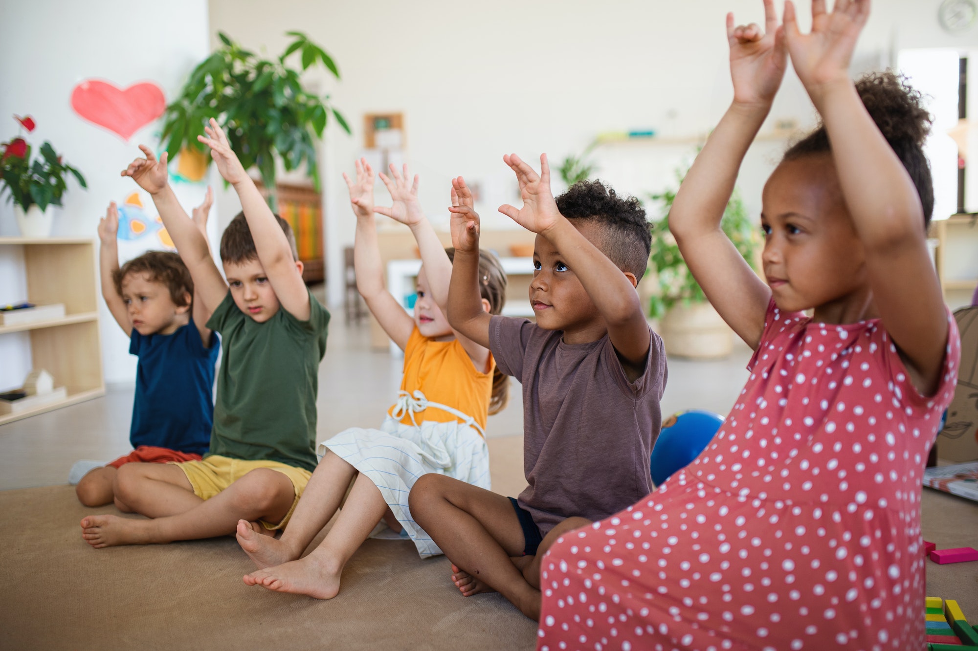 Group of small nursery school children sitting on floor indoors in classroom, playing
